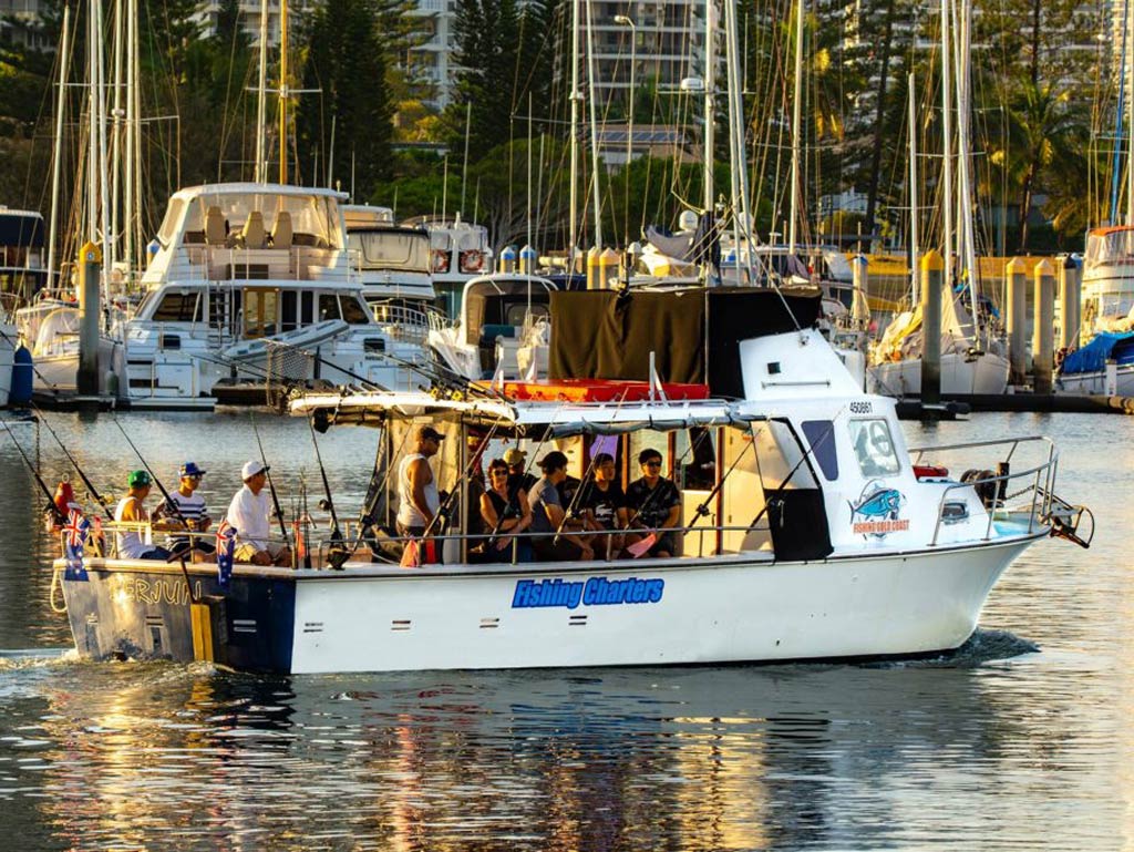 A photo depicting a party boat full of passengers standing still in the marina in Australia on a bright and sunny day