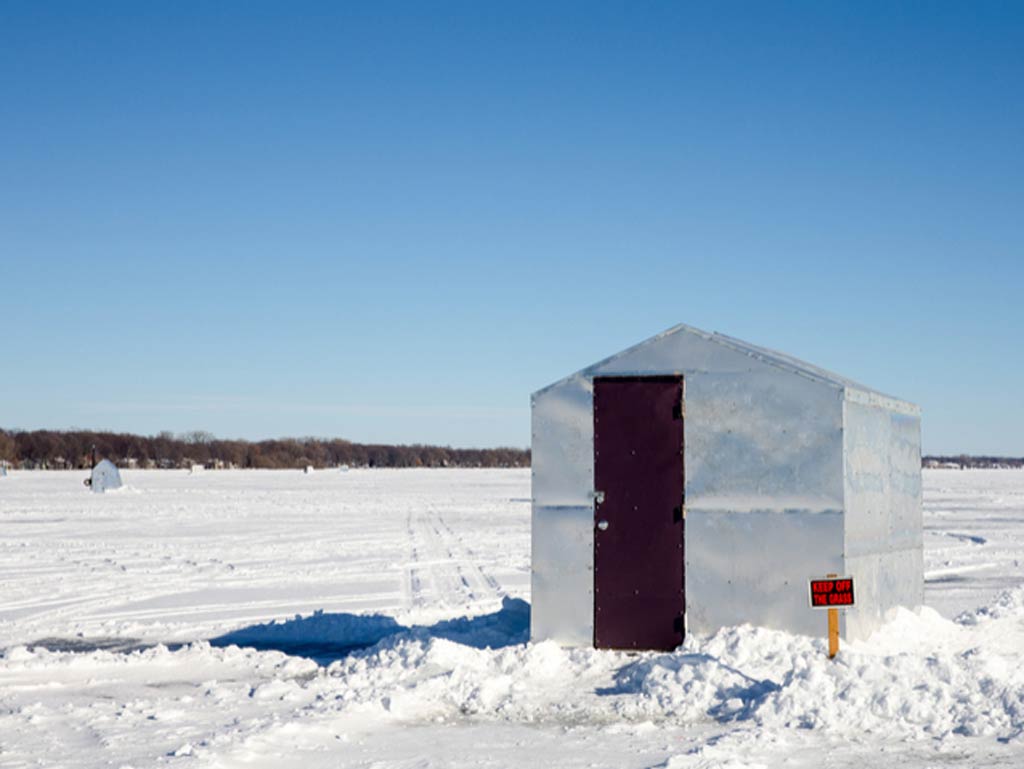 A photo featuring an ice fishing shanty on a snow-covered lake during the winter angling season