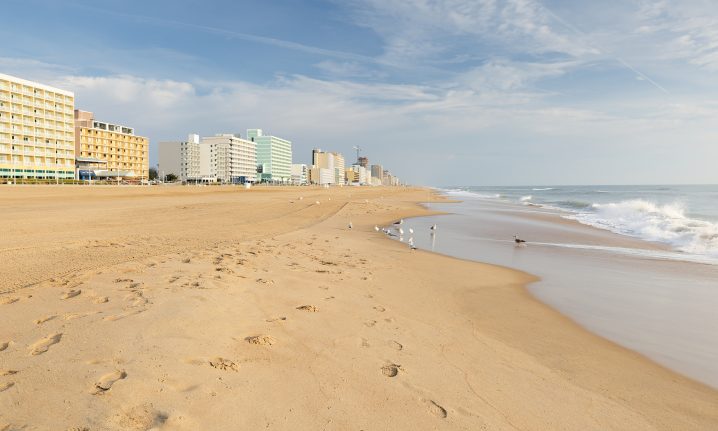 A yellow sandy beach with buildings in the left distance and sea on the right