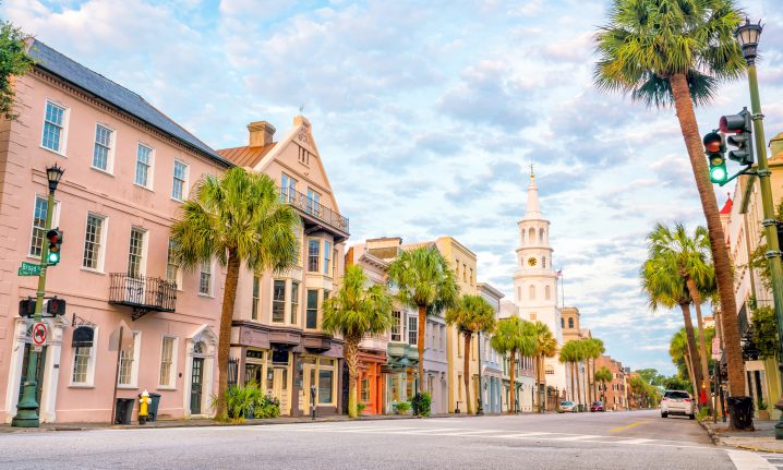 A historic street in Charleston, SC with palm trees and a blue sky