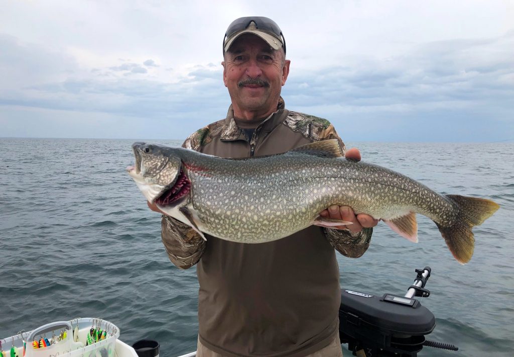 Man with lake trout on lake ontario