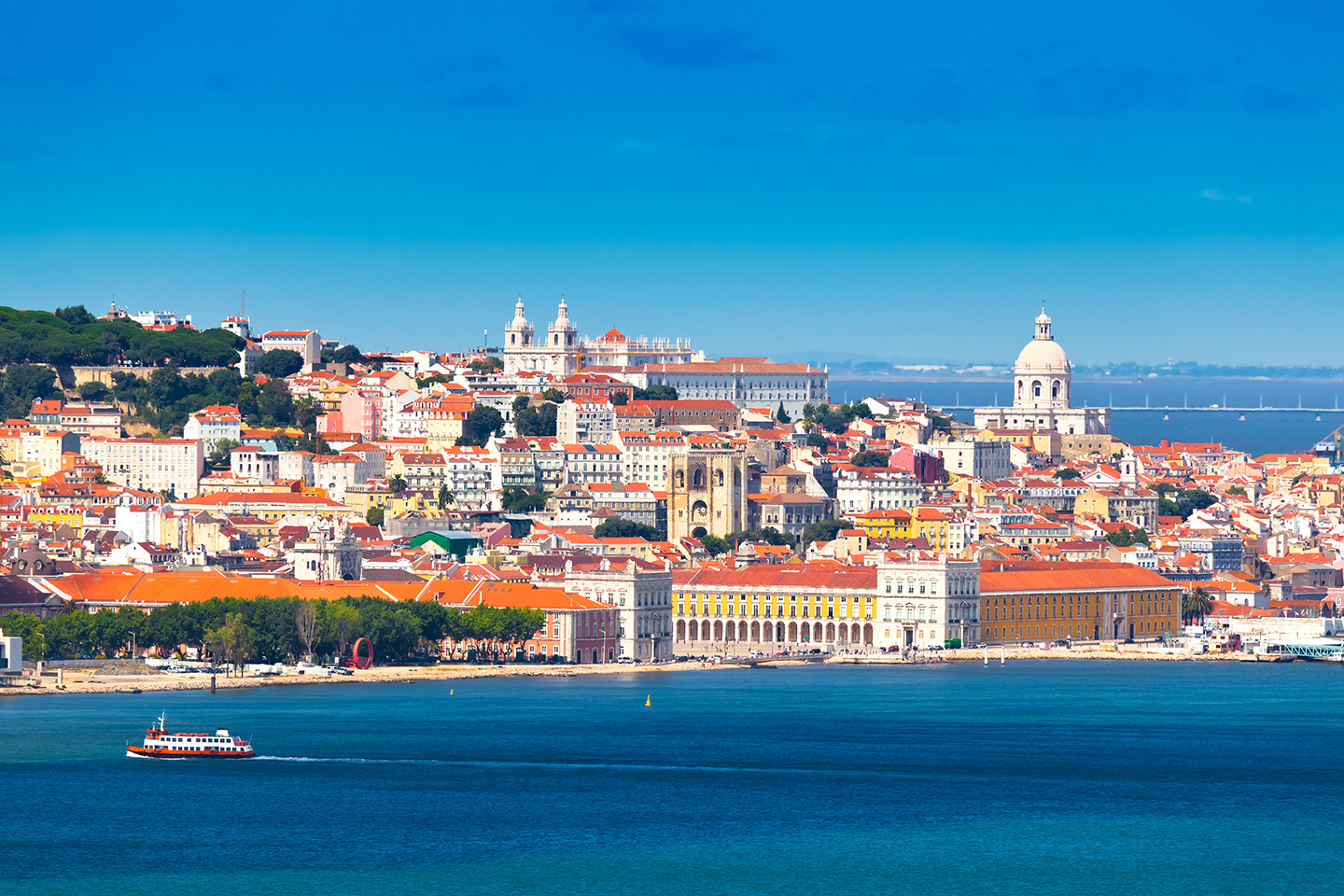 Old buildings in Lisbon, Portugal, taken from the sea with a boat in the bottom left of the photo.