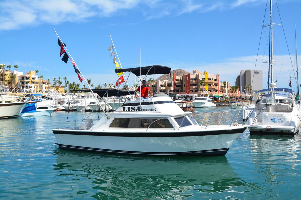 A charter fishing boat in the marina in Cabo San Lucas, Mexico, with the town and other boats in the background.