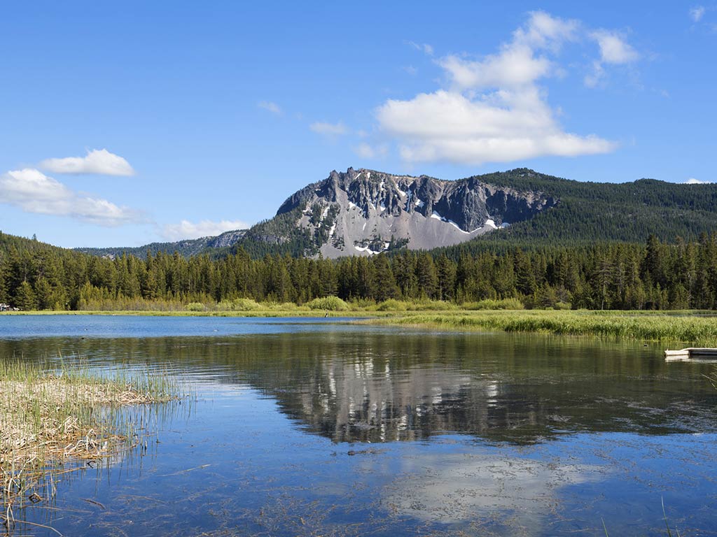 Photo showing Paulina Lake in summertime surrounded by greenery and mountains
