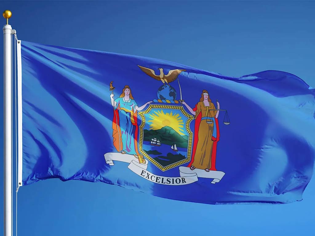 New York state flag flying atop a flagpole against a blue sky