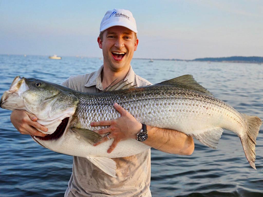 A happy angler holding a trophy-sized Striped Bass, one of the two New York State Fish