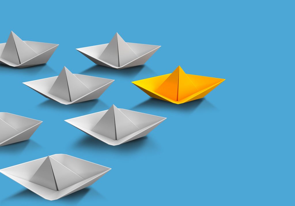 Several paper boats with one standing out