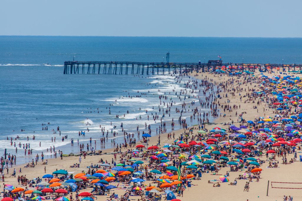 A view of a crowded Ocean City beach with the pier in the background at the height of summer