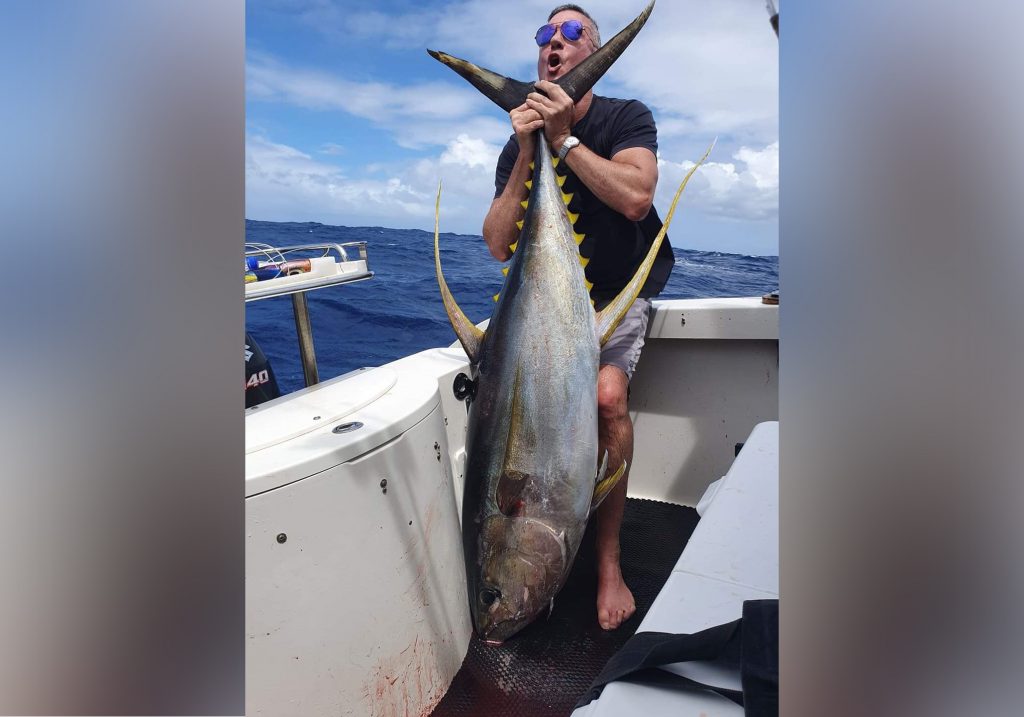 man holding yellowfin tuna on a boat