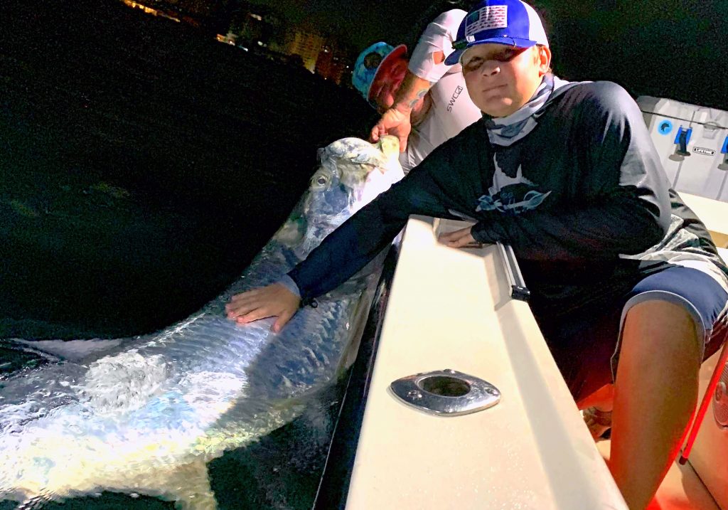 Boy in boat with huge Tarpon in the water
