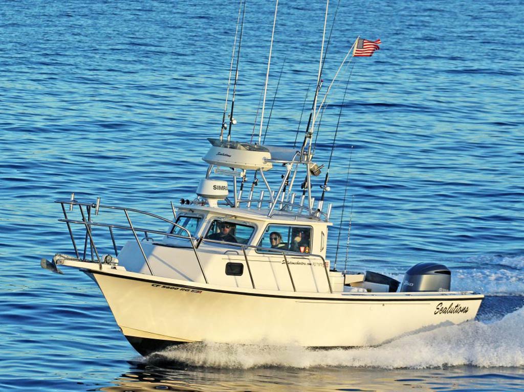 A zoomed in photo of a charter fishing boat speeding offshore in California on a bright and sunny day in attempt to find prolific angling grounds and land trophy fish