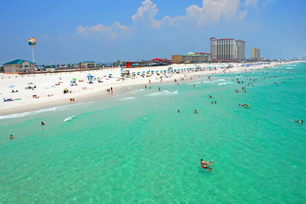 An aerial view of Pensacola Beach on a busy summer's day, with lots of people in the sea and on the beach