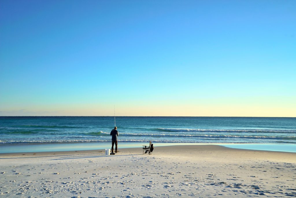 A man surf fishing on a white sandy beach in Clearwater, FL