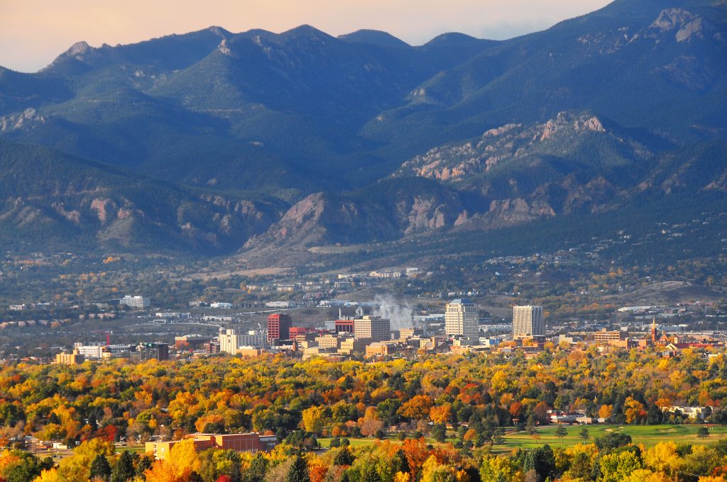 A view across yellow forest to Colorado Springs, one of the best US fishing cities. The Rocky Mountains rise in the distance.