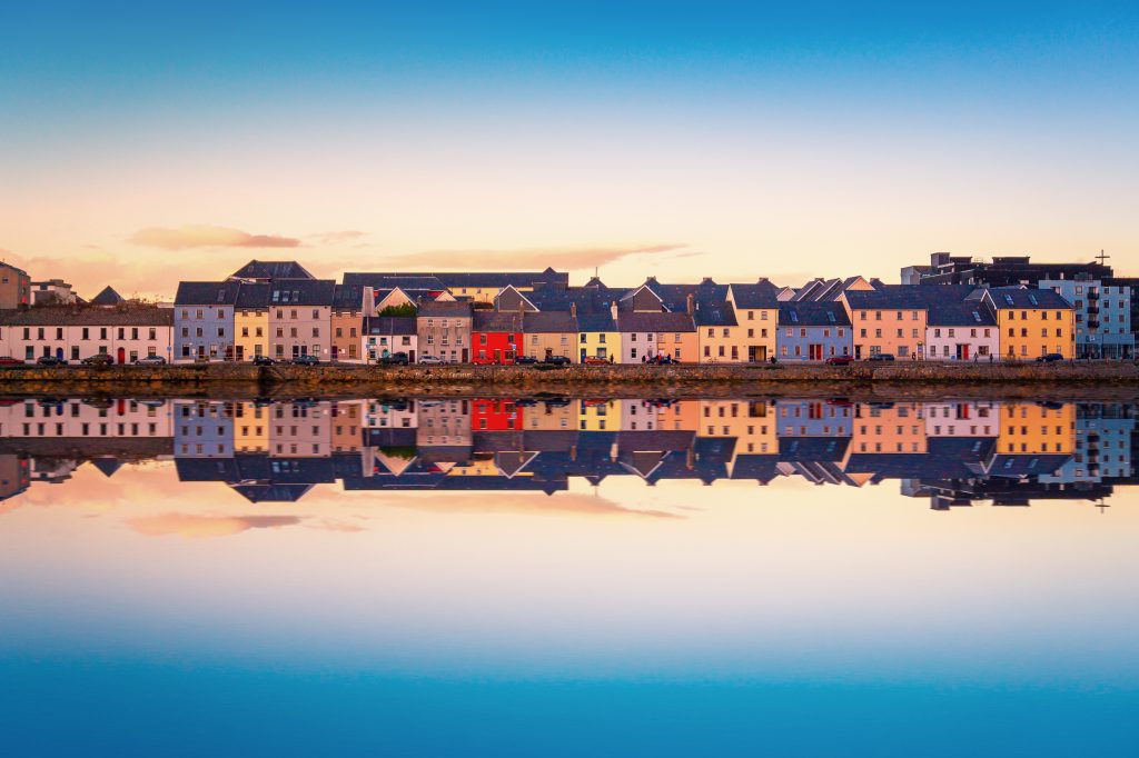 Galway waterfront at dawn. Old buildings are reflected in the water, giving a mirror image