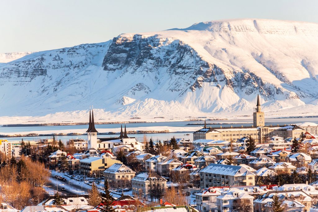 An aerial view over Reykjavik, Iceland, with snowy mountains in the distance