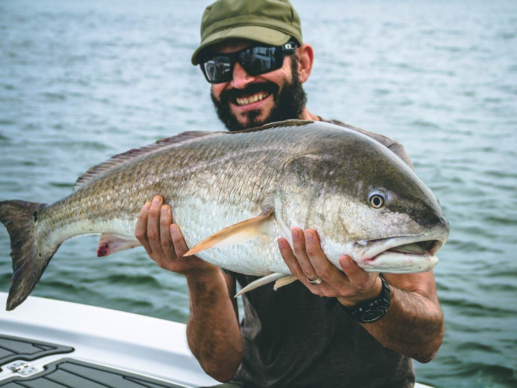 An angler holding a large Red Drum caught while fishing in Charleston, SC