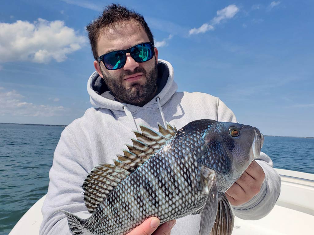 A man holding a Black Seabass on a charter boat