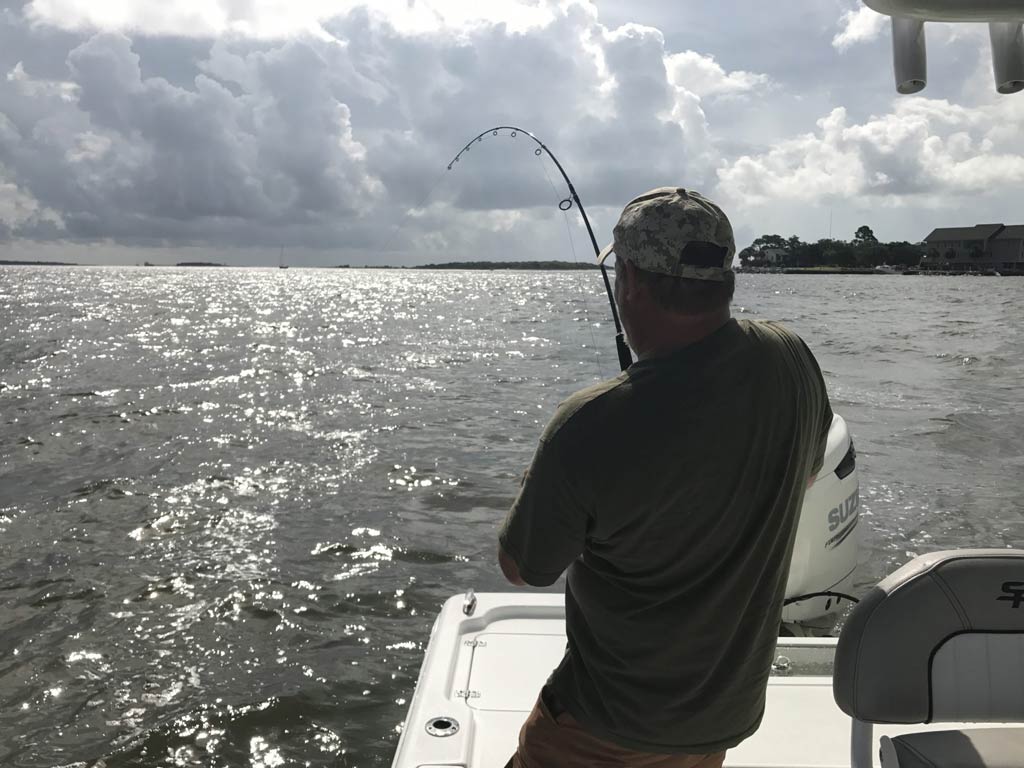 An angler fighting a fish on a boat near Folly Beach, SC