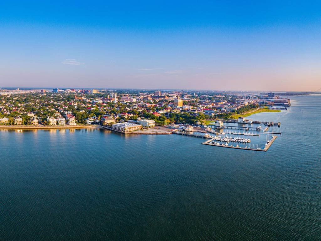 An aerial view of Charleston, SC at sunset, looking across the water towards the city.