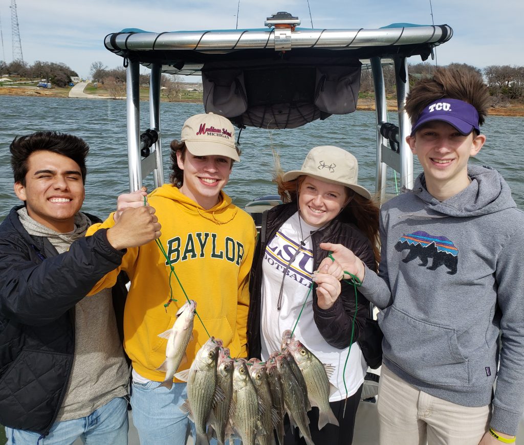 Four teenagers holding their catch of White Bass