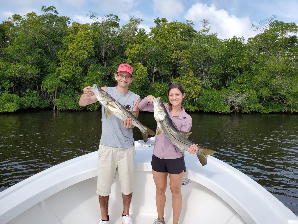 A man and a woman holding two big Snook fish