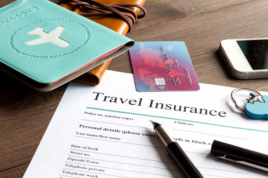 A travel insurance form, with a pen, credit card, and mobile phone lying near it