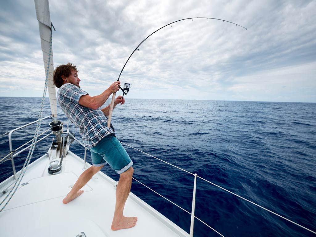 Man Rigging Deep Sea Fishing Poles On Fishing Boat Off The North