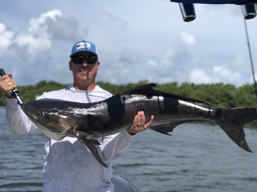 A happy angler holding a big Cobia on a boat