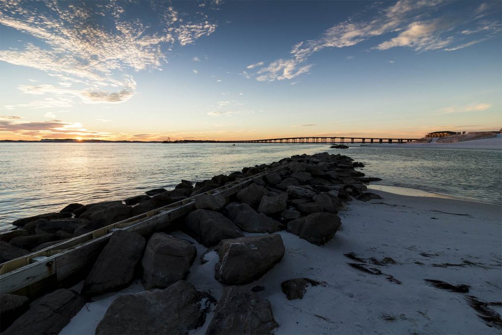 An image of the rocks looking towards Destin across the bay at sunset