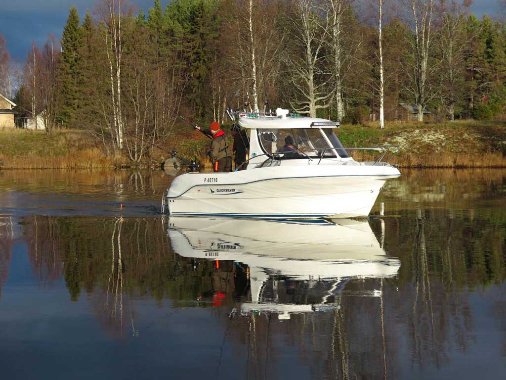 A charter boat in Finland on the water with a crew and customers fishing from the back of the boat