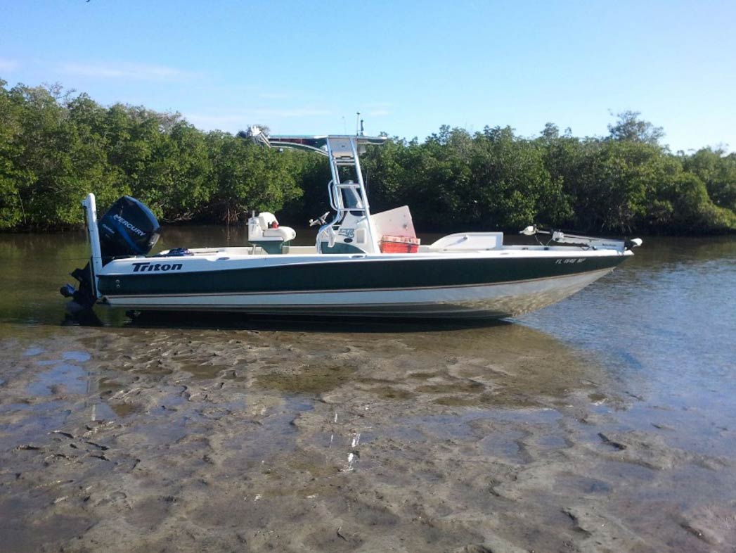 An inshore fishing vessel rests on the shallow waters of Fort Pierce on a clear sunny day