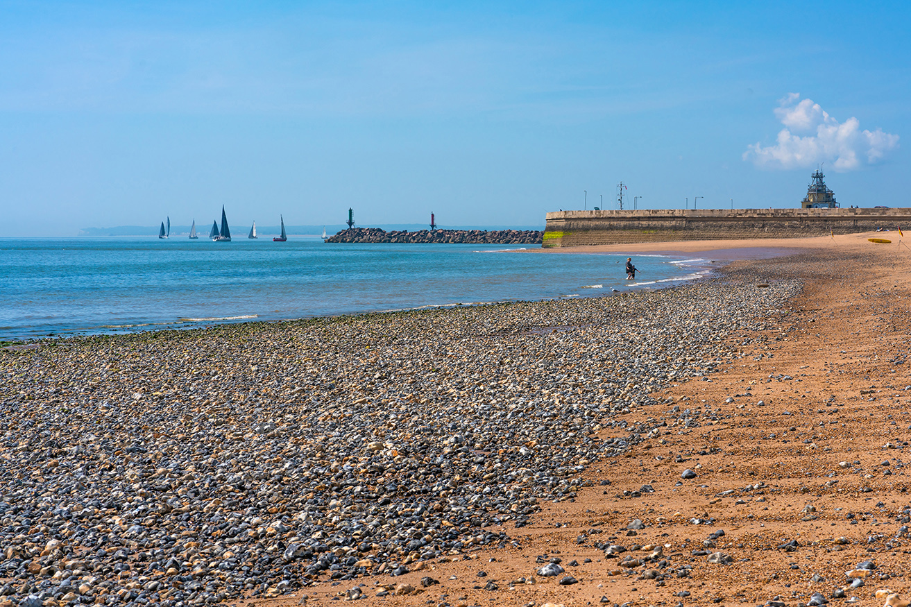 Ramsgate Beach at low tide, with the harbour wall and sailboats in the distance