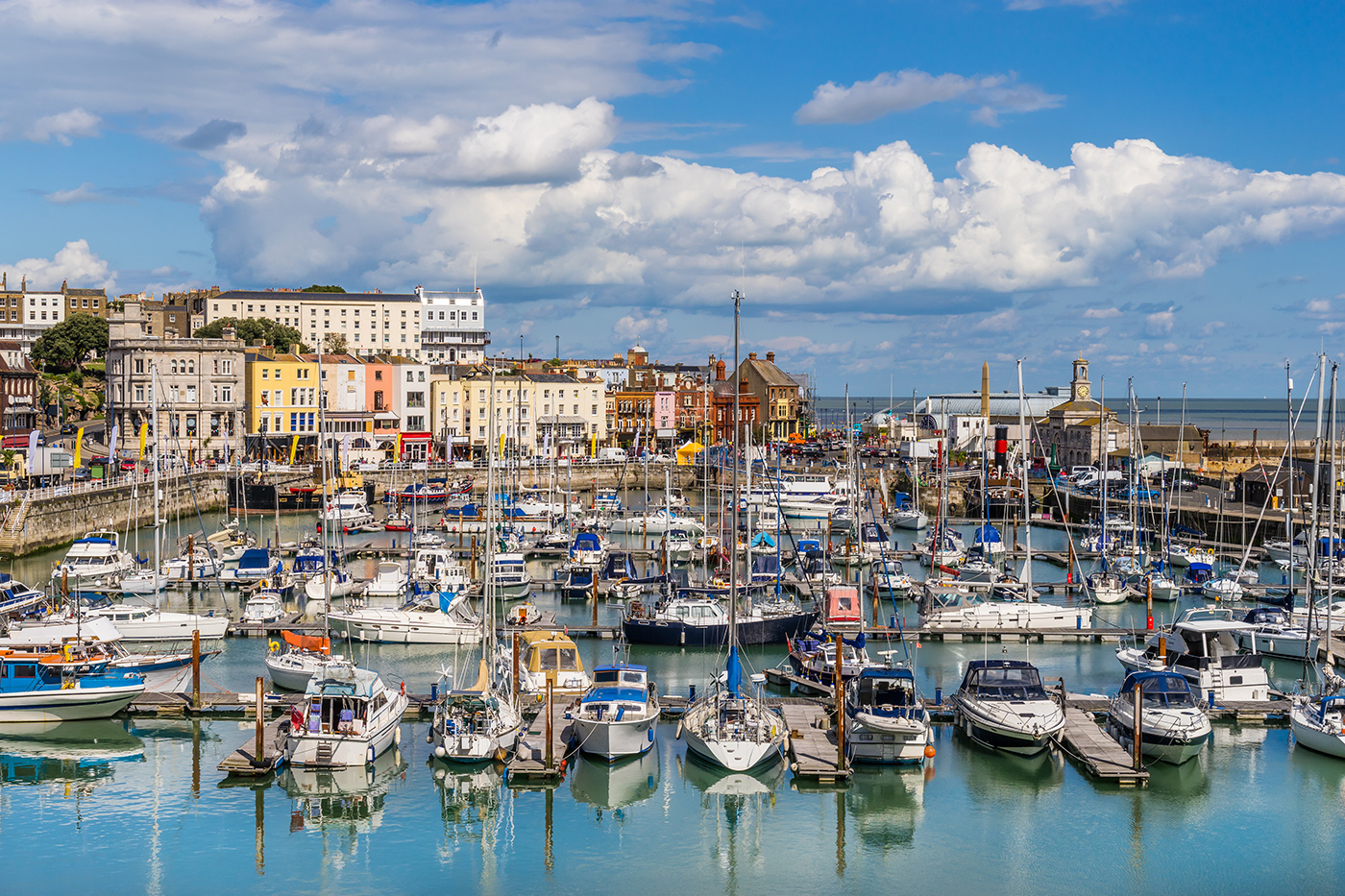 A sunny day at Ramsgate Harbour, with boats in the water and pretty buildings in the distance