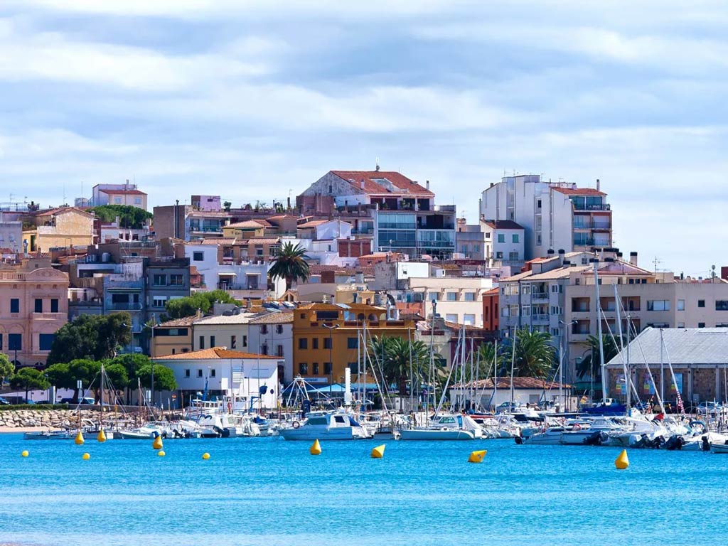 A view of Mallorca's skyline, with the sea in the forefront and charter boats docked