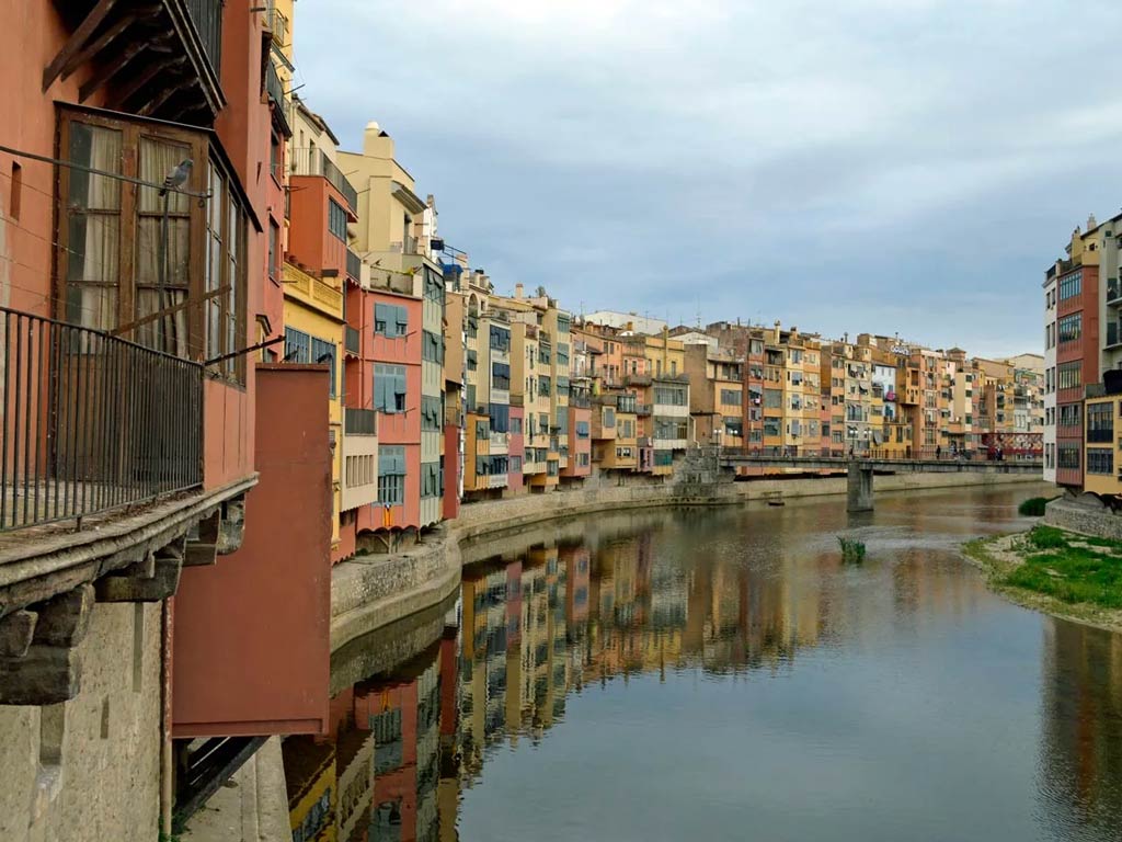 An urban view of the river Ter, with buildings to the left of the image and the river to the right