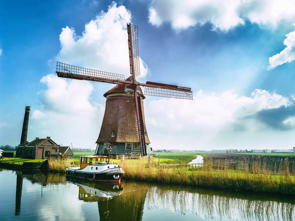 A boat on the waters of the Netherlands overlooking a big windmill