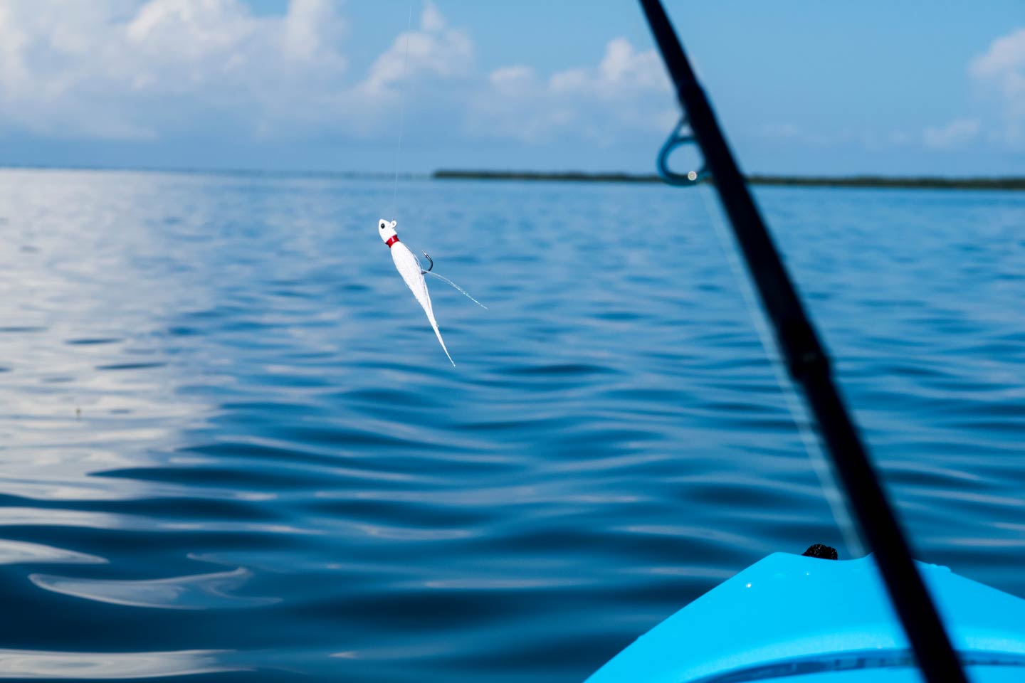 A white lure on a fishing rod above the water, taken from a kayak while fishing
