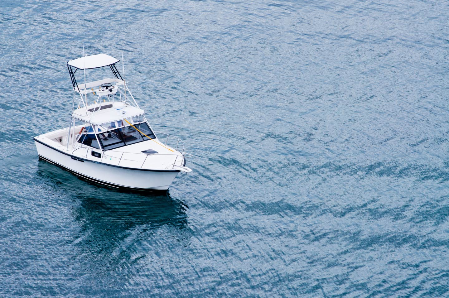 An aerial view of a large charter boat  with a flybridge making its way quietly through calm waters