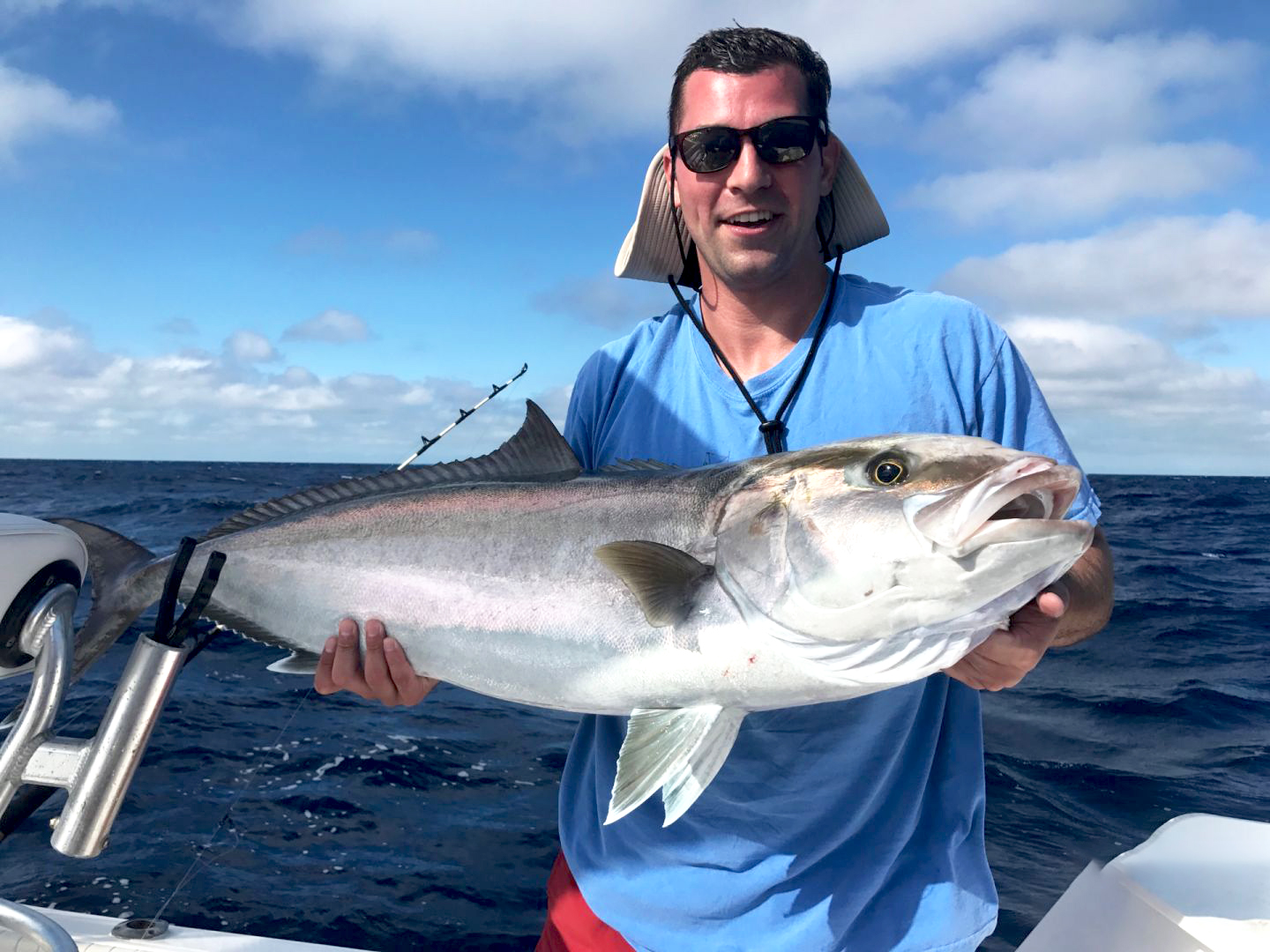 A man holding an Amberjack on a boat