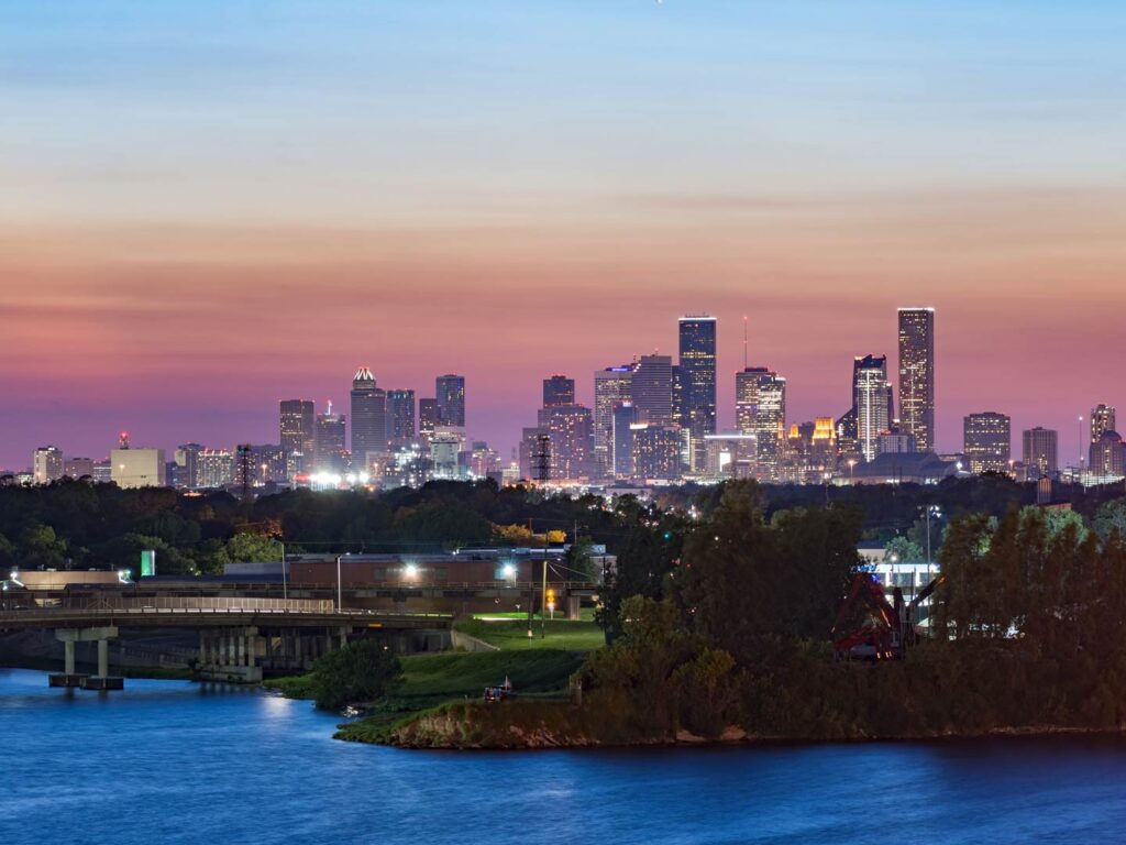 Sunset over Houston, TX as viewed from docks, with the city's skyline visible.