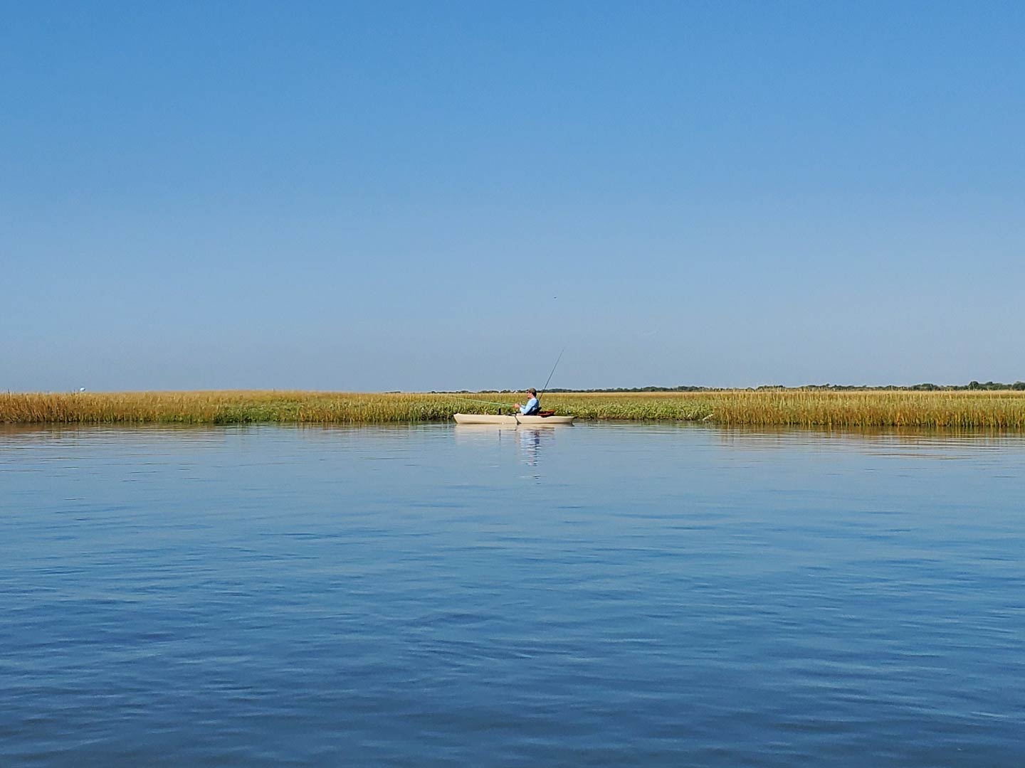 A view from the water across to a fishing kayak on the backcountry waters of Galveston Bay
