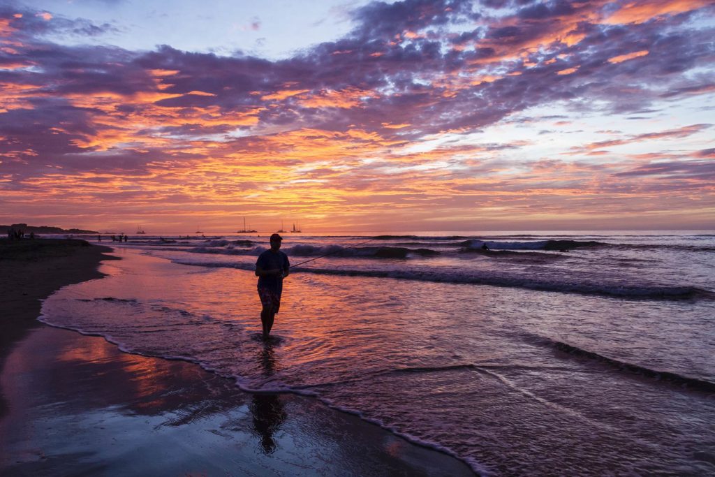 A silhouette of an angler casting from the shore into the inshore waters at sunset in Costa Rica