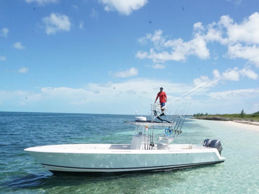 A charter captain on his boat's tower with clear waters and clear skies in the background