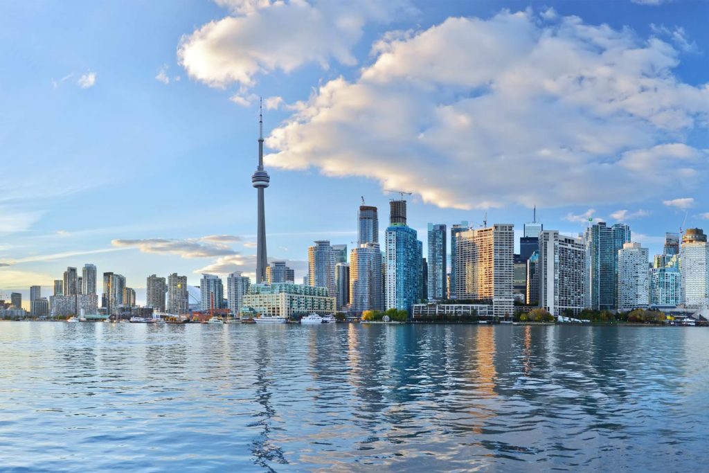 A view of the Toronto skyline as seen from Lake Ontario with clouds above the city on a relatively sunny day.