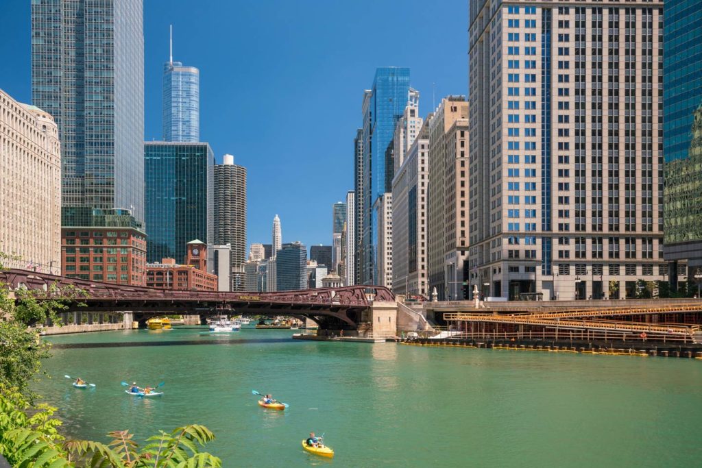 A view of kayakers on the Chicago River with skyscrapers and bridges