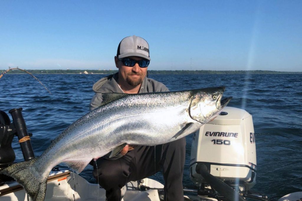 A man holds a large Chinook Salmon on board a charter boat on Lake Michigan