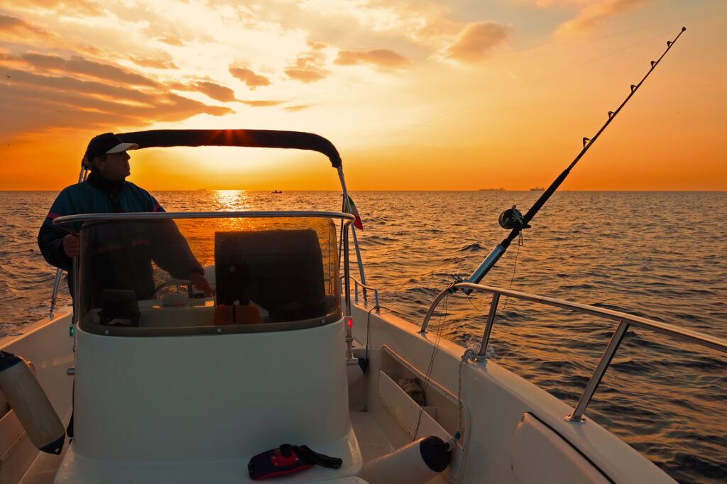 Ein Angler auf einem Fischerboot im Morgengrauen.