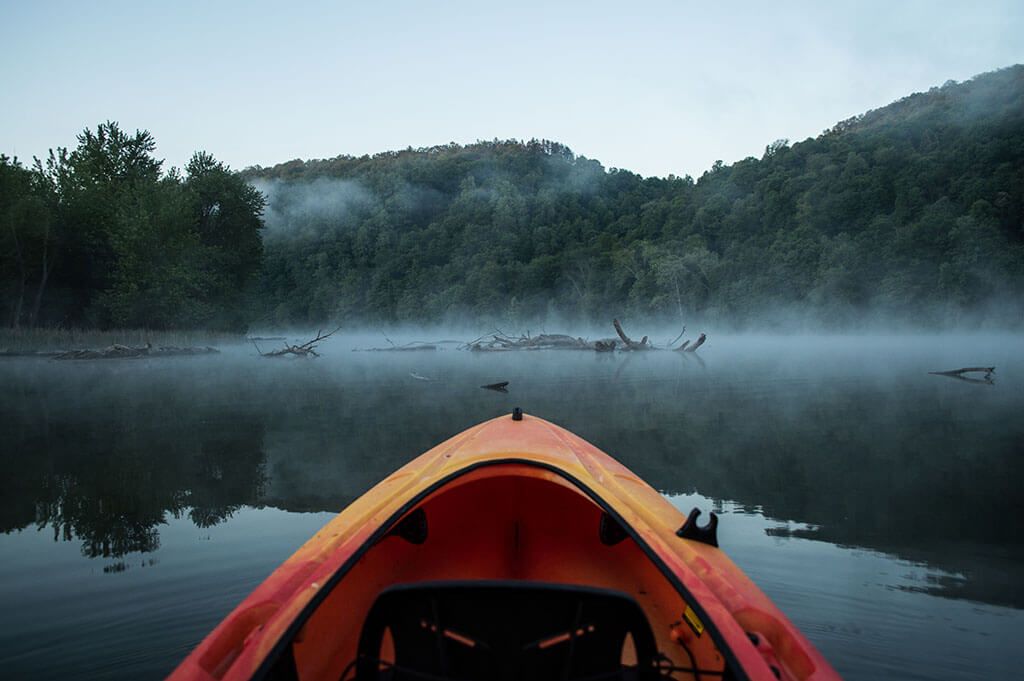 A view from a kayak on the Juniata River, one of the best spring fishing spots in the US, with a forest in the background.