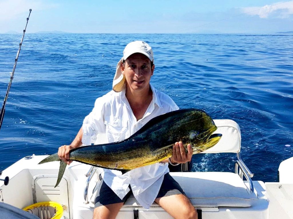 An angler holding a Mahi Mahi on a boat in Panama City Beach